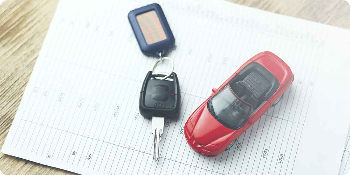 Ein Spielzeugauto liegt mit dem Autoschlüssel auf den Fahrzeugdokumenten.