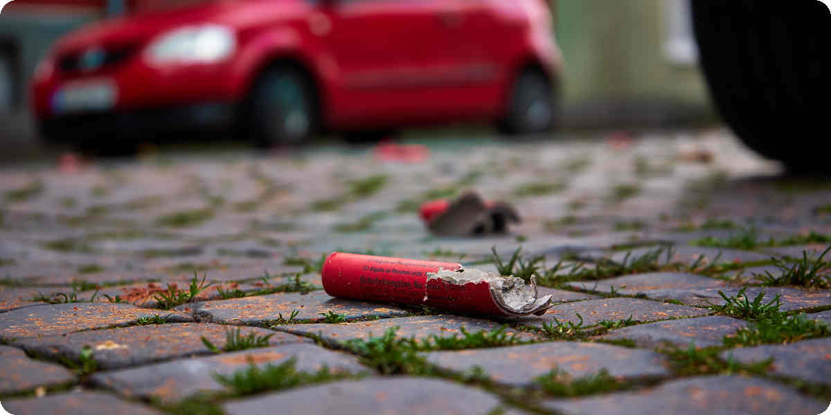 Explodierter Silvesterböller liegt auf dem Boden neben dem Auto.