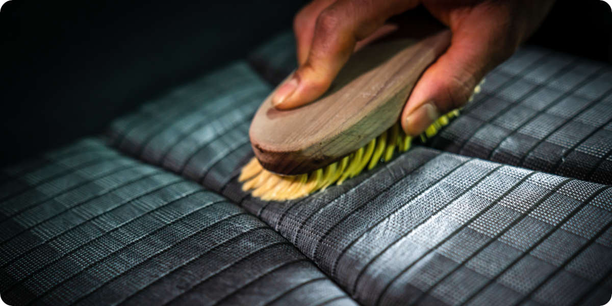 Ein Autopolster wird mit einer Bürste gereinigt. 