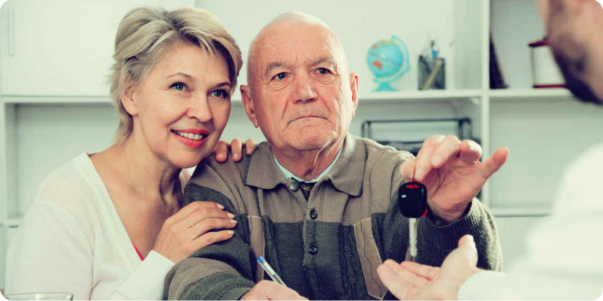 Eltern uebergeben Ihren Autoschlüssen an Ihr Familienmitglied.