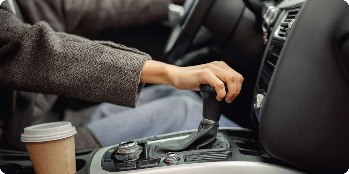 Eine Frau schaltet mit der Hand in den nächsten Gang und betätigt dafür die Kupplung.