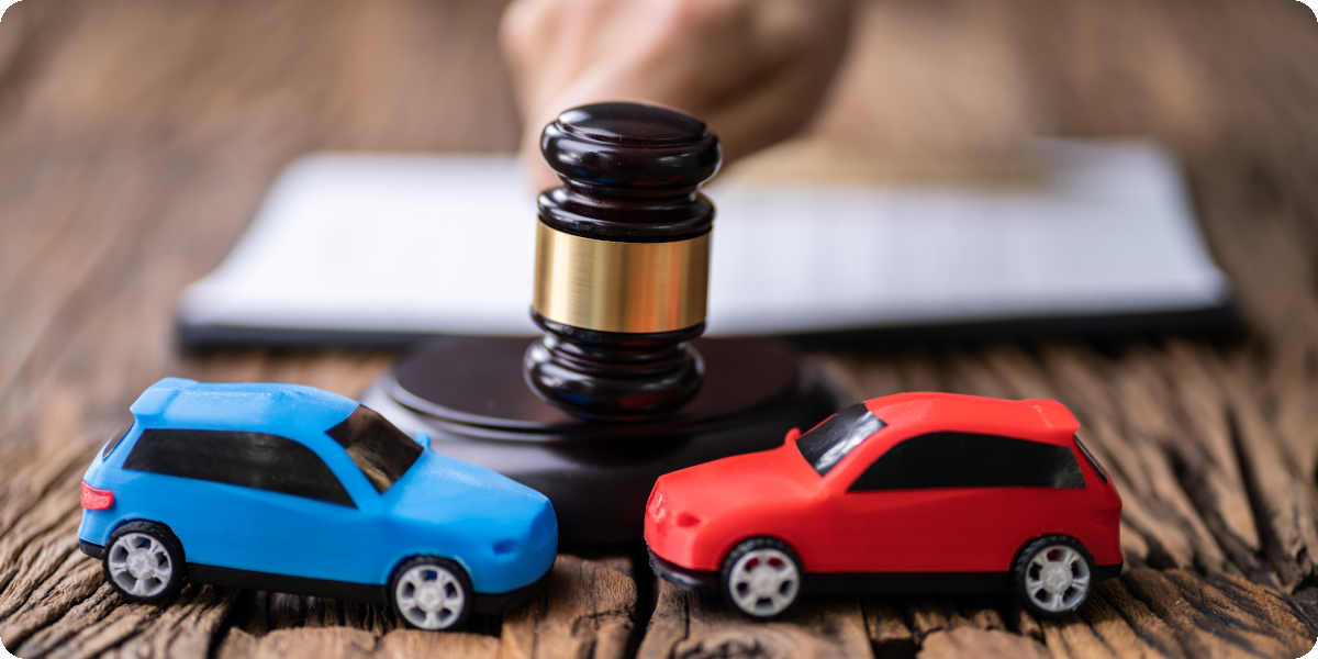 Zwei Spielzeugautos stehen vor dem Hammer eines Richters.