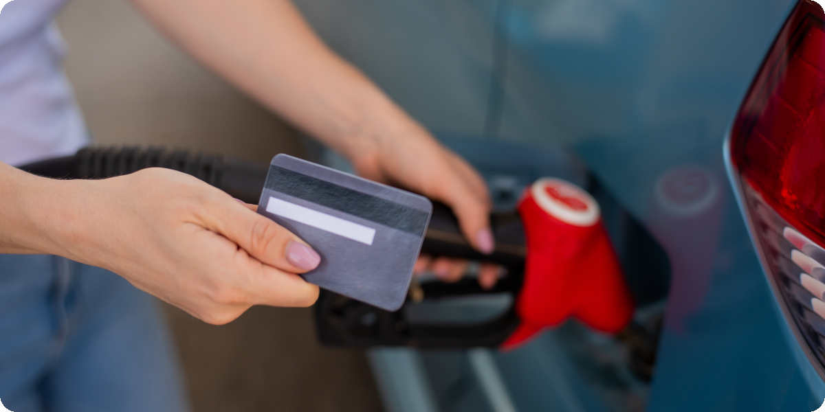 Ein Auto wird betankt und eine Person zeigt seine Tankkarte vor.