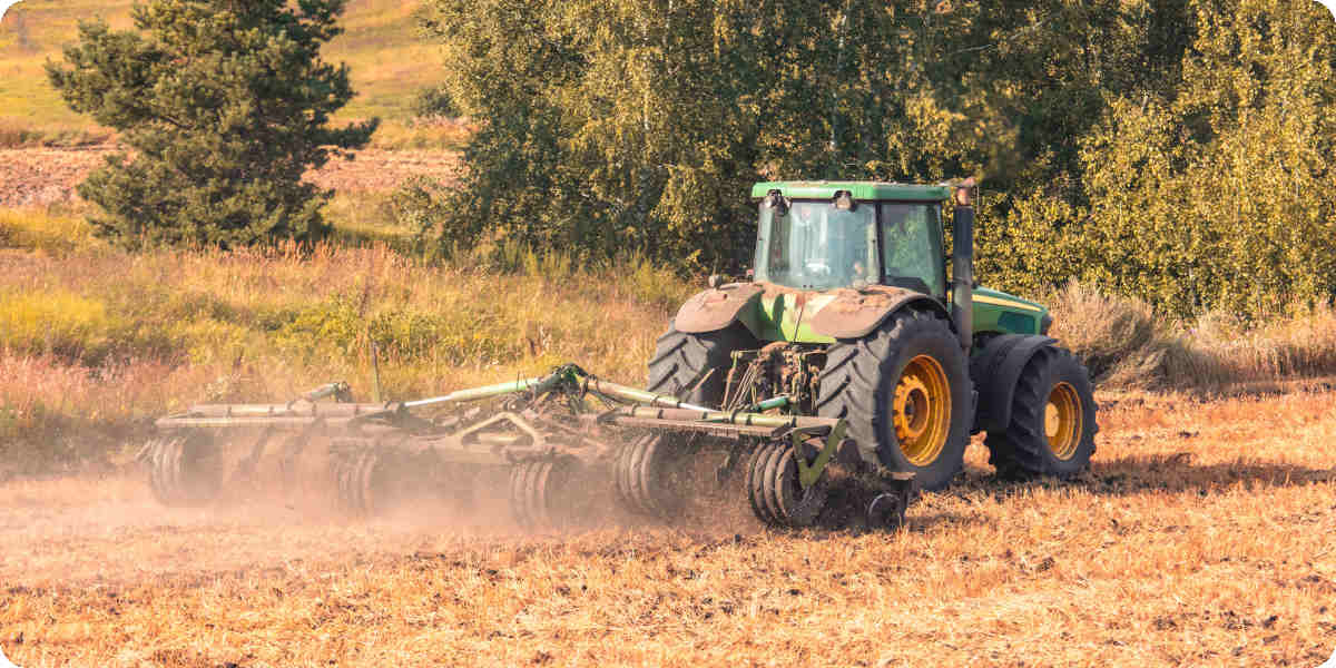 Ein Traktor pflügt den Boden in ein Feld.