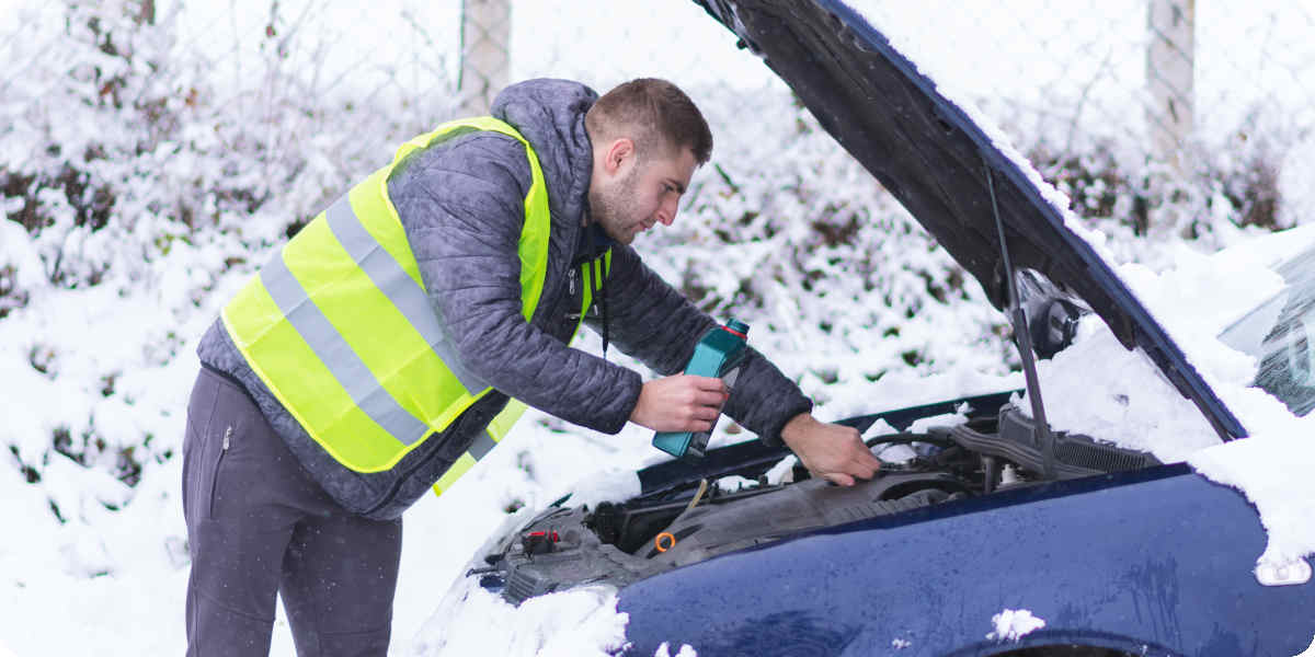 Autofahrer füllt im Winter das Frostschutzmittel im Kühlmittel nach.