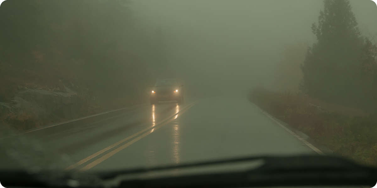 Sichtbehinderung während der Autofahrt durch Nebel und Regen.