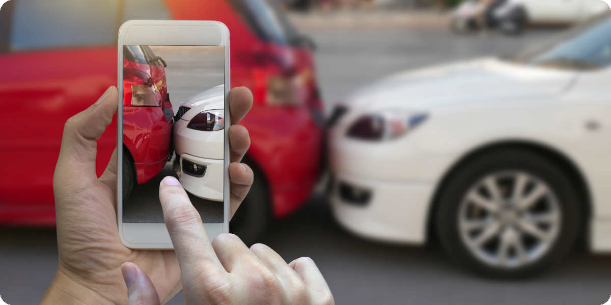 Eine Person macht ein Bild mit seinem Smartphone von dem Auffahrunfall für die Kfz-Versicherung.