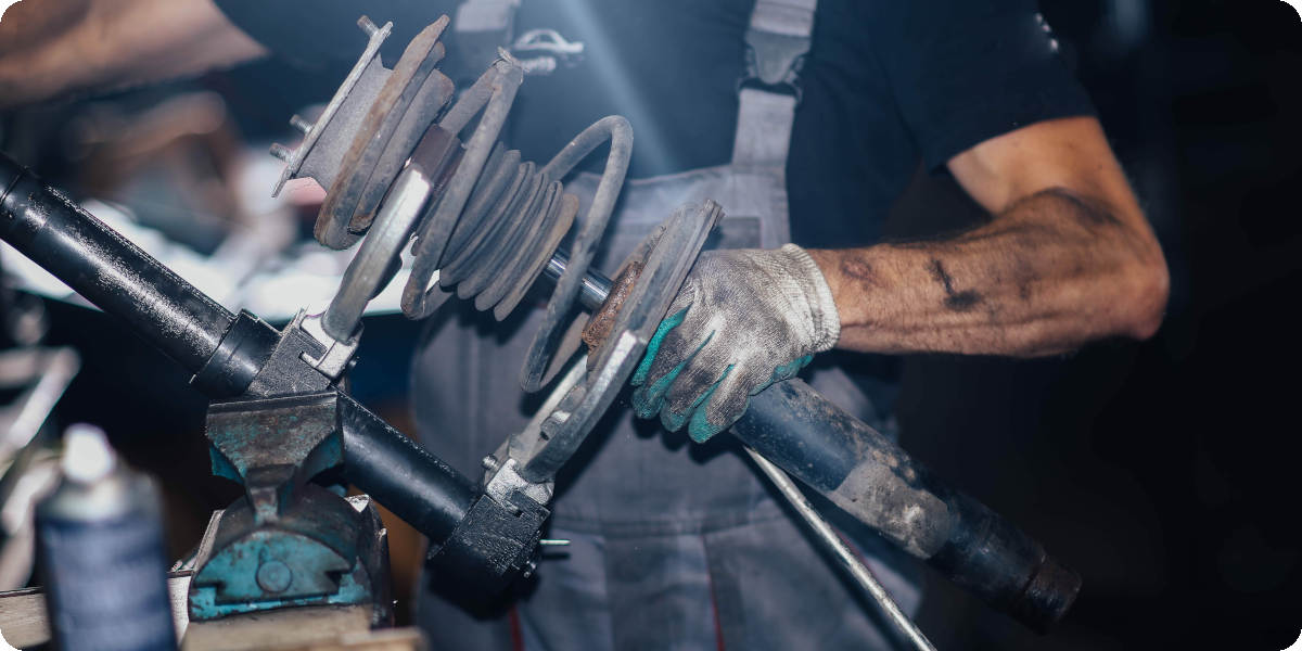 Mechaniker hält einen Stoßdämpfer in der Hand.