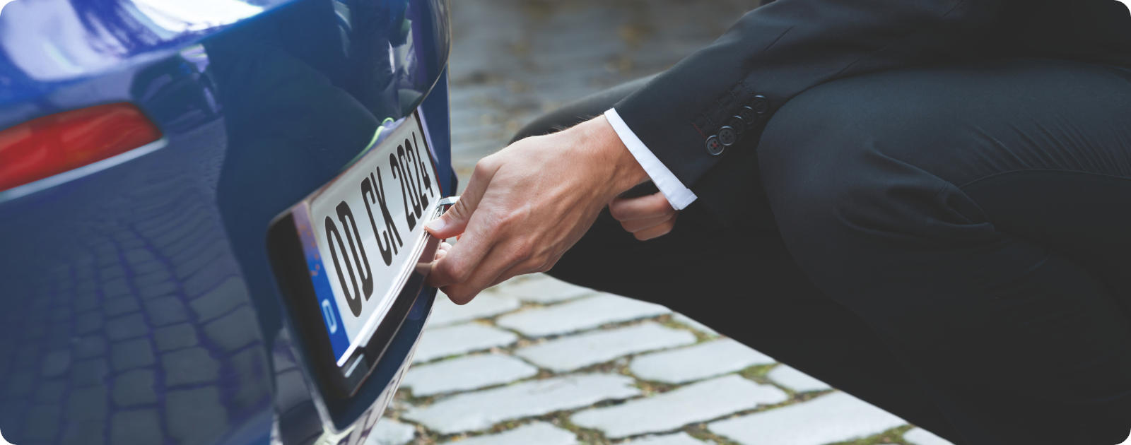 Eine Person baut das hintere Kennzeichen des Autos für die Abmeldung ab.